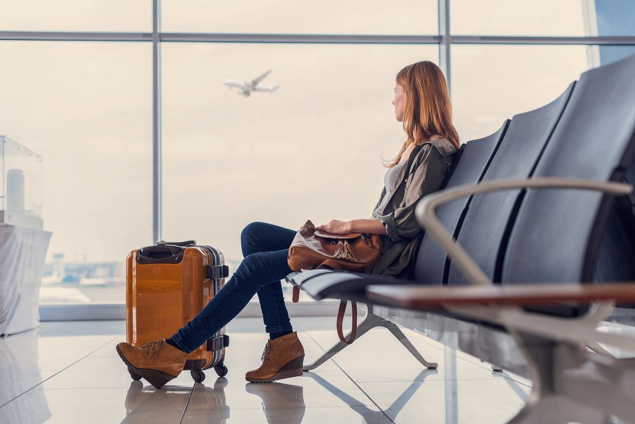 Woman waiting at airport with suitcase.