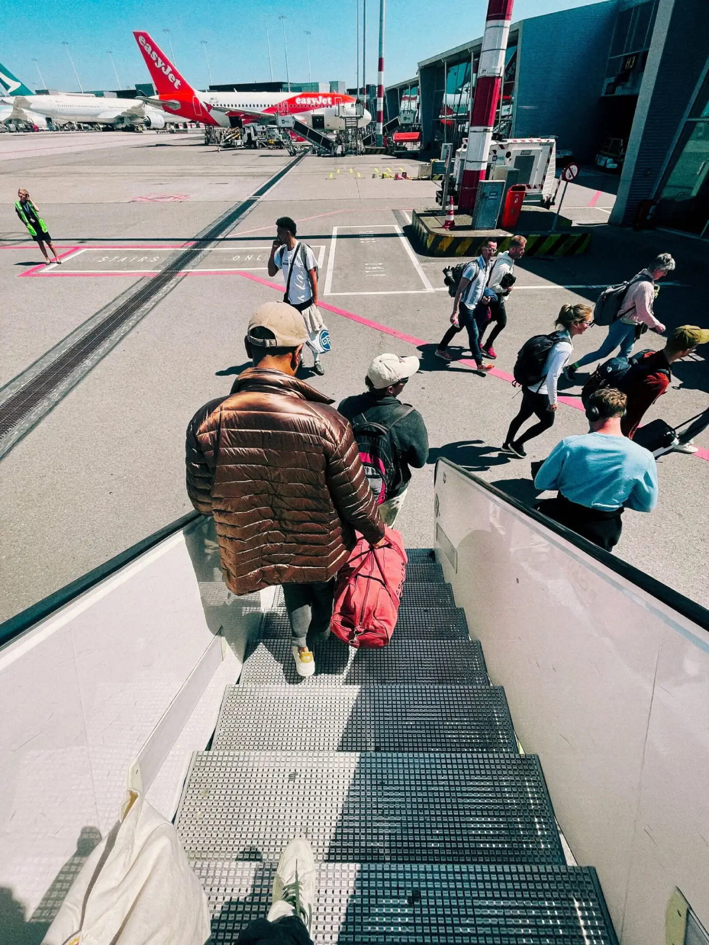 Passengers disembarking airplane onto airport tarmac.